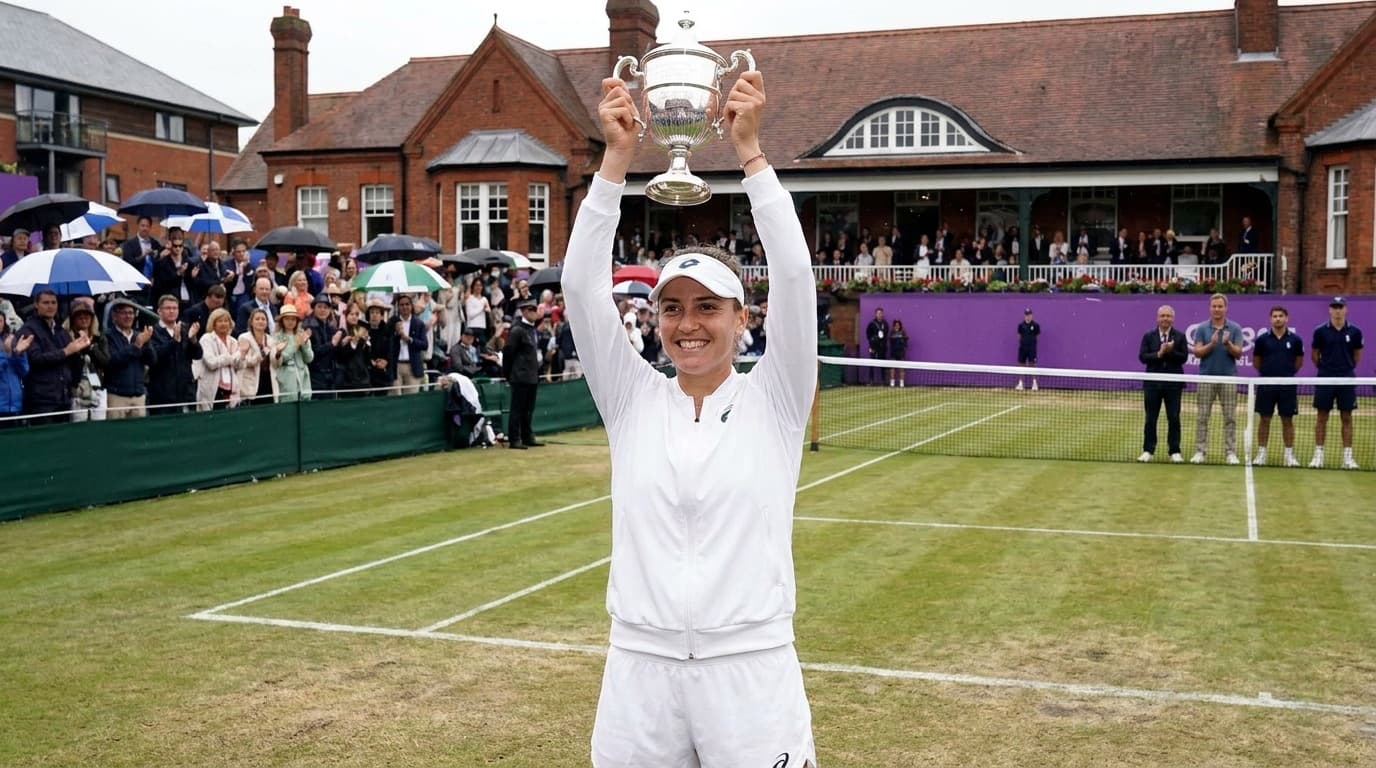 A women's tennis player raises the trophy on grass at Queen's Club in London