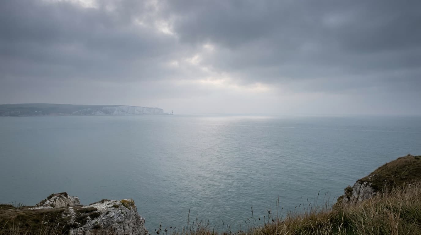 Generic view of the English Channel coastline with calm grey water under an overcast sky, no identifiable individuals