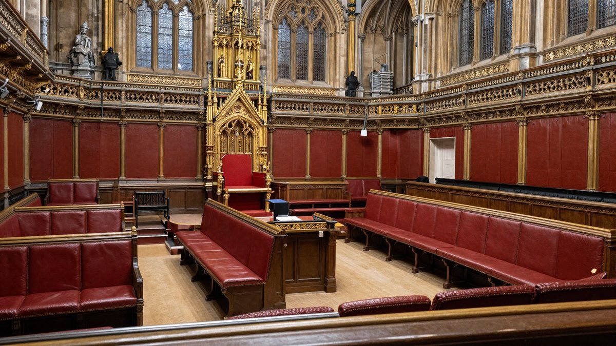 The gilded interior of the House of Lords chamber prepared for the State Opening of Parliament with the throne and red benches