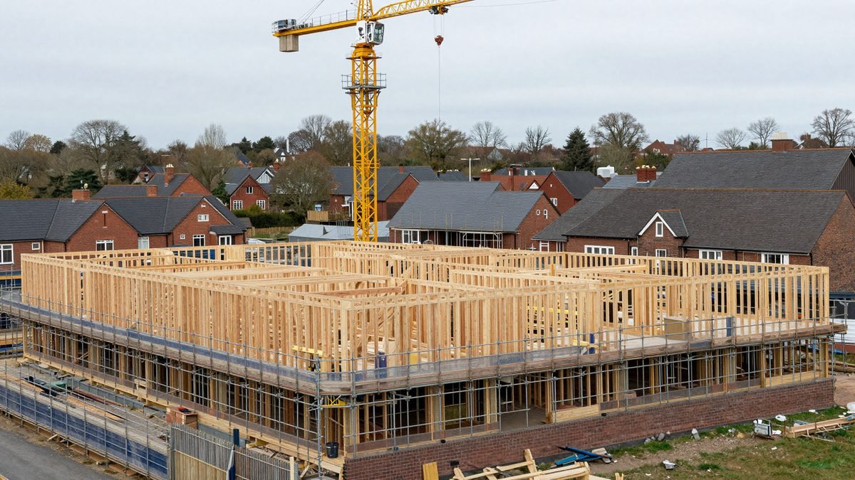 A new housing development under construction with scaffolding and cranes on the edge of a town